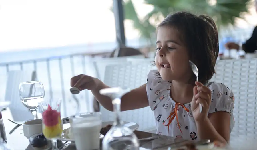 Deniz kıyısında restoranda yemek yiyen kız çocuğu - aile-otelleri -Elbis Hotel Altınoluk